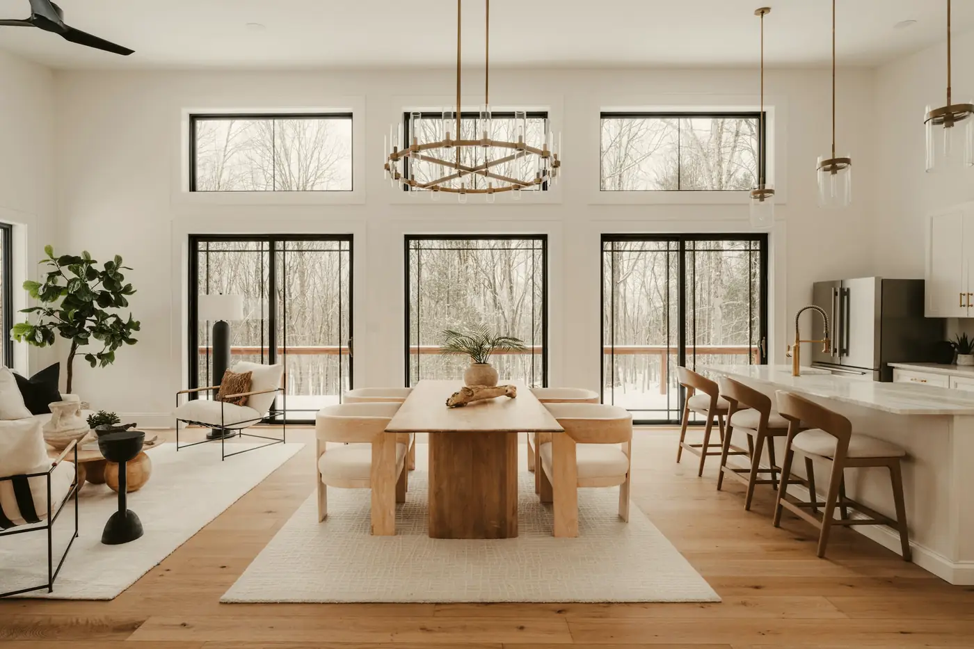 A bright new open-plan dining room and kitchen with tall black-framed windows onto trees