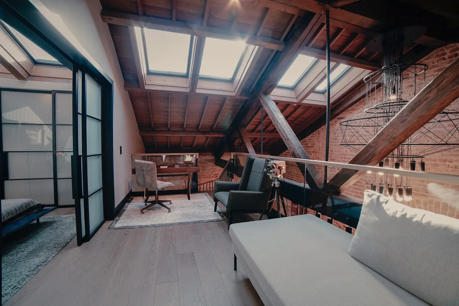 A finished loft room under exposed rafters, rooflights and a glazed partition