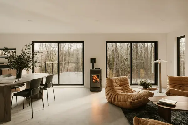 A finished open-plan living room with a wood-burning stove and tall windows onto trees